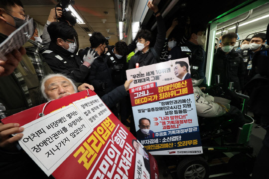 전국장애인차별철폐연대(전장연) 회원들이 지난 13일 오전 서울 용산구 4호선 삼각지역에서 출근길 지하철 탑승 시위를 하고 있다. 서울시는 이날 출근길부터 전장연 시위로 열차 운행이 지연되면 무정차 통과하기로 했으나 이날 삼각지역에 무정차한 열차는 없었다.<연합뉴스>